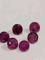 Six round faceted rubies on white background