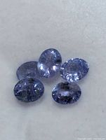 Five oval violet-blue tanzanite gemstones close-up