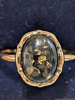 Top view showing oval cabochon with gold flecks in bezel setting