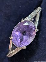 Top view of silver ring with oval purple stone and CZ shoulders