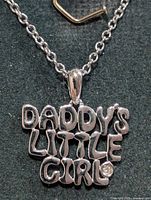 Pendant close-up showing lettering and diamond accent