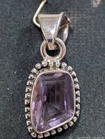 Front view of silver pendant featuring rectangular amethyst with beaded edge