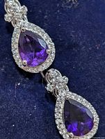 Close-up of two amethyst CZ drops showing stone color and halo setting