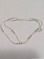 Full view of silver bead station necklace laid flat