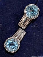 Front view showing both earrings with blue topaz stones and milgrain bezels