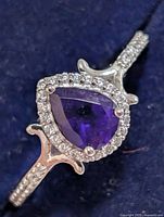 Top view showing pear-shape purple stone with halo of clear stones