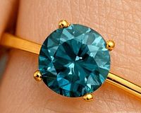 close-up of blue lab diamond in gold prong setting
