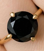 Close-up of black diamond in four-prong yellow gold setting