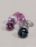 Close view of seven assorted fancy-color sapphires on white background