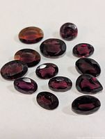 Loose faceted garnet gemstones spread on white surface