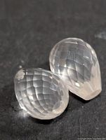 Two faceted pear briolette rose quartz gems on dark background
