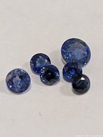 Five loose round blue sapphires grouped together on white background
