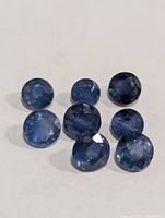 Eight round blue faceted sapphires on white background