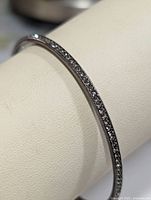 Side view of silver bangle showing channel-set CZ stones