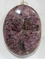 Front view of oval purple gemstone pendant in silver bezel