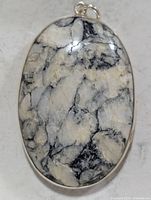 Front view of oval marbled gemstone pendant in silver setting