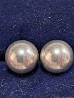 front view of two silver ball studs displayed on dark fabric