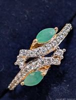 Top view of ring showing two marquise green stones and clear CZ accents