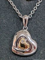 Close-up of heart pendant front view; shows two-tone design and diamond accent