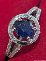 Top view showing oval blue center stone, surrounding CZ halo, split shank
