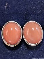 front view of both oval peach cabochon gemstone earrings in silver setting