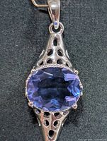 Front view of silver pendant highlighting tanzanite stone and openwork design