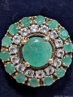 Top view of ring showing emerald centre, clear stone and emerald halo