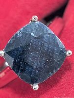 Front view of ring showing cushion-cut dyed sapphire and prongs