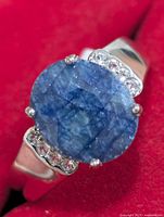 Front view of silver ring showing oval blue gemstone and accent stones