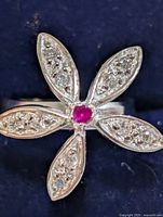 Top view of silver flower ring showing CZ in petals and red center stone