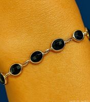 Close-up of bracelet on wrist showing bezel-set blue sapphires and gold links