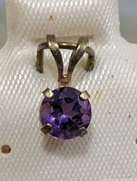 Front view of 10K gold pendant displaying round amethyst in four-prong setting