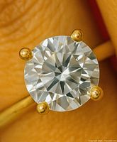 Close-up of round brilliant lab diamond in yellow gold four-prong setting