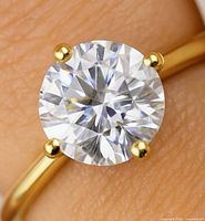 Close-up of round lab diamond set in yellow gold prongs