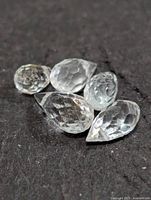 Five faceted aquamarine stones on dark background