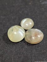 Three loose cat's eye cabochon gemstones on black surface