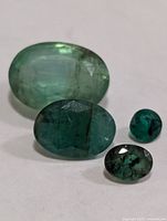 Four faceted emeralds showing relative sizes and colors