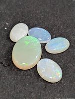 Five oval opal cabochons on dark background