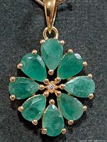 Front view of pendant showing emerald arrangement, prongs, bail
