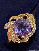 Close-up front view of silver ring with purple center stone and clear accents