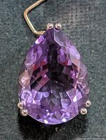 Front view showing pear-shaped faceted amethyst in silver prong setting