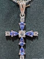 Close-up of cross pendant front showing tanzanite stones and clear accents