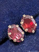 Close-up of both garnet stud earrings showing stones, prongs and silver setting