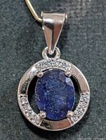 Front view of silver pendant showing blue oval stone and CZ border