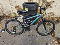 Left side view of entire Supercycle mountain bike leaning against stack of tires