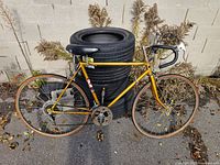 Full view of yellow CCM road bicycle leaning on tire stack