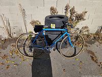 Full left side view of blue road bicycle leaning against stacked tires