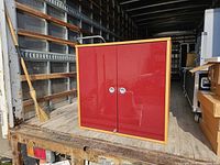 Front view of cabinet showing red glossy doors and metal knobs