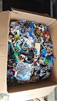 Overview of cardboard box filled with assorted loose LEGO pieces