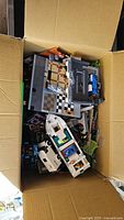 Opened cardboard box showing assorted Lego pieces and partial builds